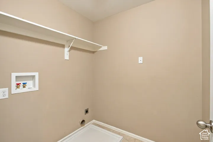 Dedicated laundry area featuring a wall-mounted shelving unit, recessed water hookups, and a recessed dryer exhaust vent