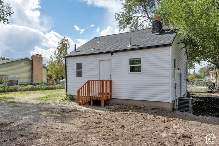White horizontal siding exterior featuring a gable roof, a brick chimney, and an attached wood-stain staircase