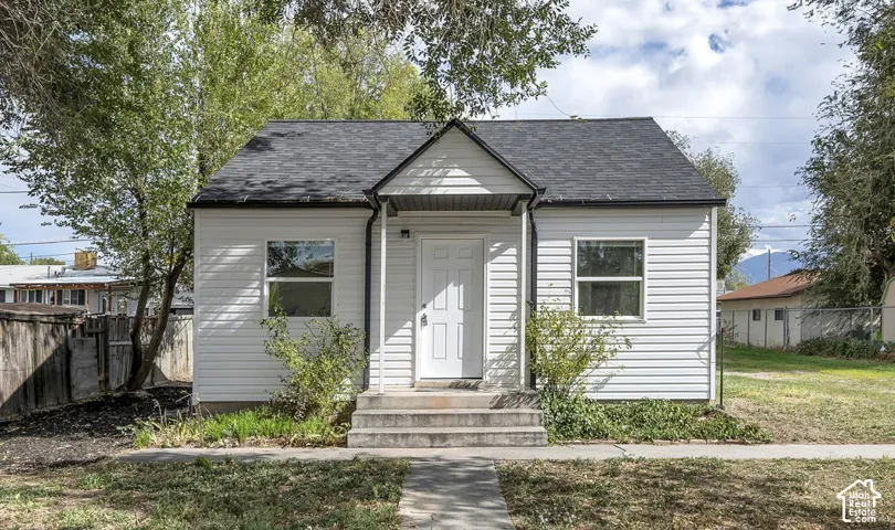 Exterior featuring white horizontal siding, dark-toned shingle roofing, a gabled front entry portico, and concrete steps