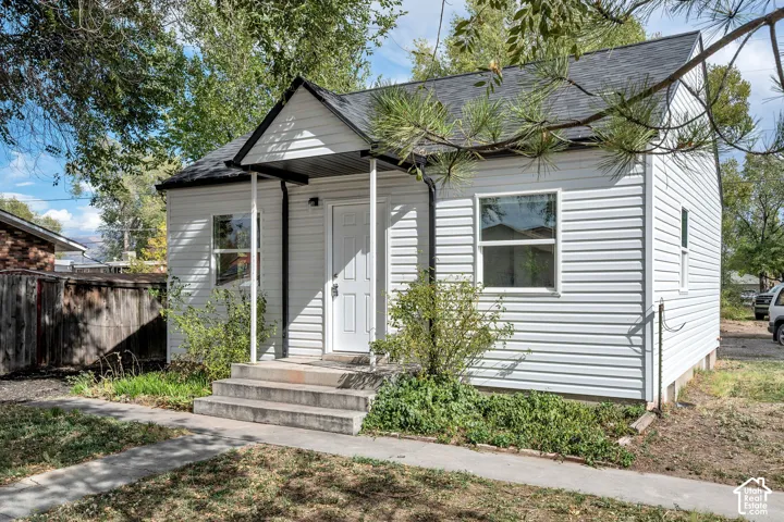 Exterior featuring white horizontal siding, dark grey shingle roofing, and a front-facing gable with a covered porch