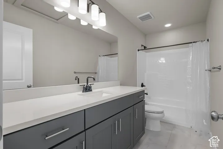 Bathroom featuring a dark gray vanity with a solid surface countertop, an undermount sink, matte black fixtures, and a tub-shower combination with full-height tile surround