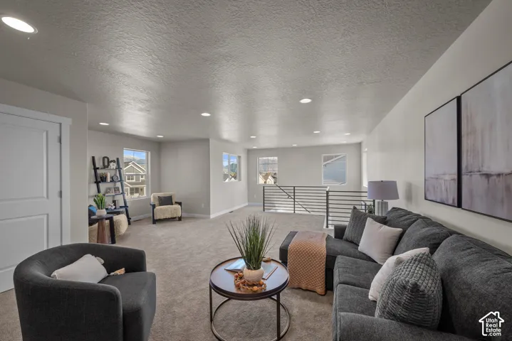 Open-concept interior featuring recessed lighting, carpeting, and a metal horizontal-bar railing