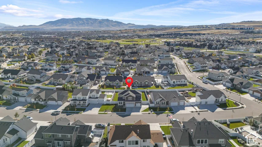 Aerial perspective of a multi-story residence featuring a two-car garage, fenced backyard, and mountain backdrop