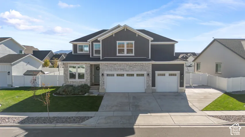 Two-story exterior featuring vertical board-and-batten siding, stone veneer accents, a three-car garage, and a concrete driveway