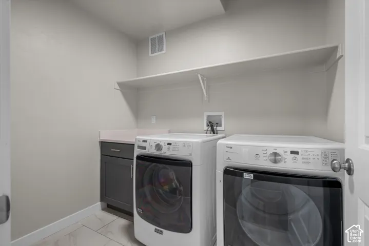 Laundry room featuring tile flooring, a charcoal-finished base cabinet with a solid-surface countertop, and a wall-mounted shelving unit