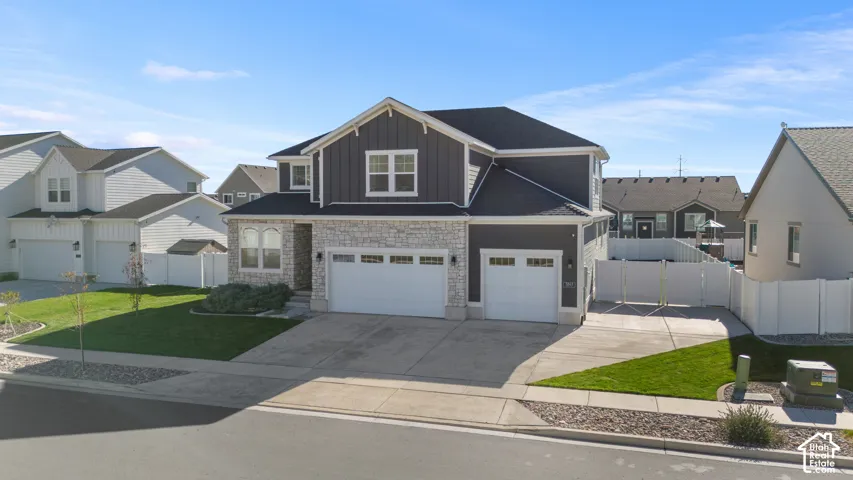 Two-story exterior featuring stone veneer and vertical siding, three-car garage, and gated side yard access