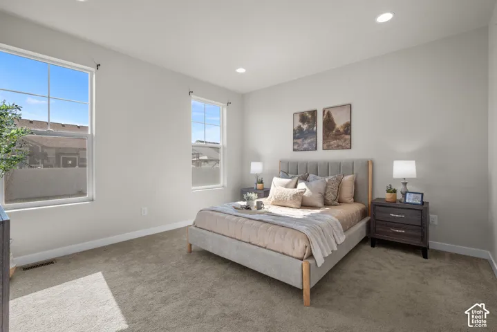 Neutral-toned interior space featuring neutral wall paint, plush carpeting, recessed lighting, and dual grid-patterned windows