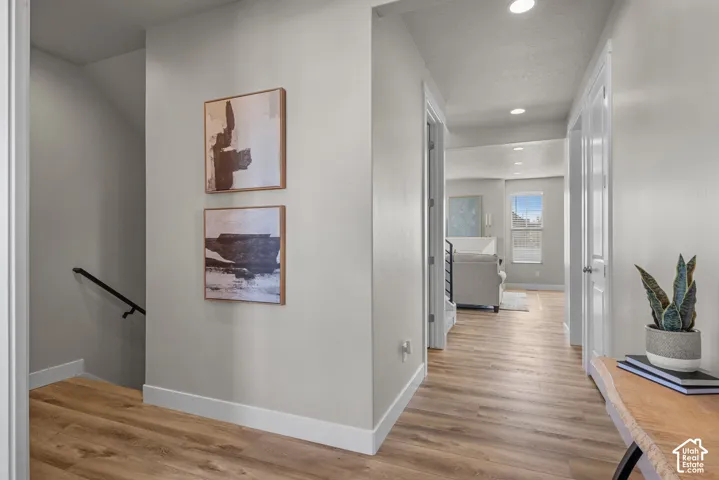 Wood-finish flooring, recessed lighting, and a metal stair railing