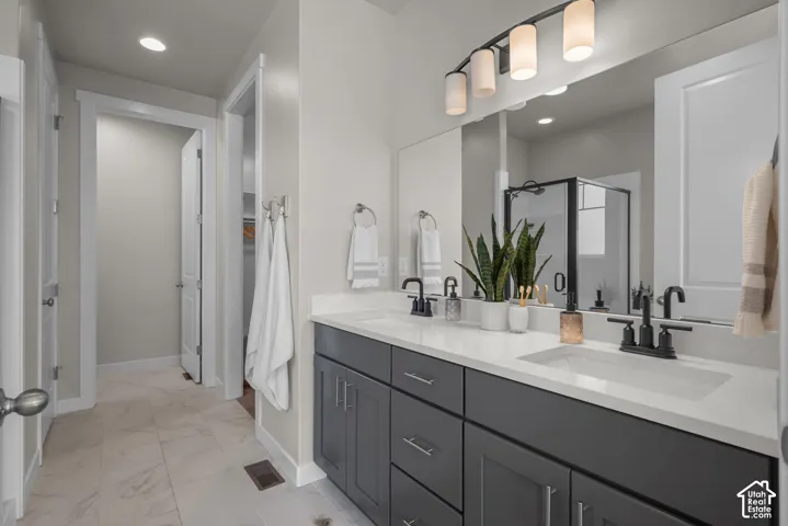 Dual-sink vanity with matte black fixtures, quartz countertop, charcoal cabinetry, and a large wall-mounted mirror