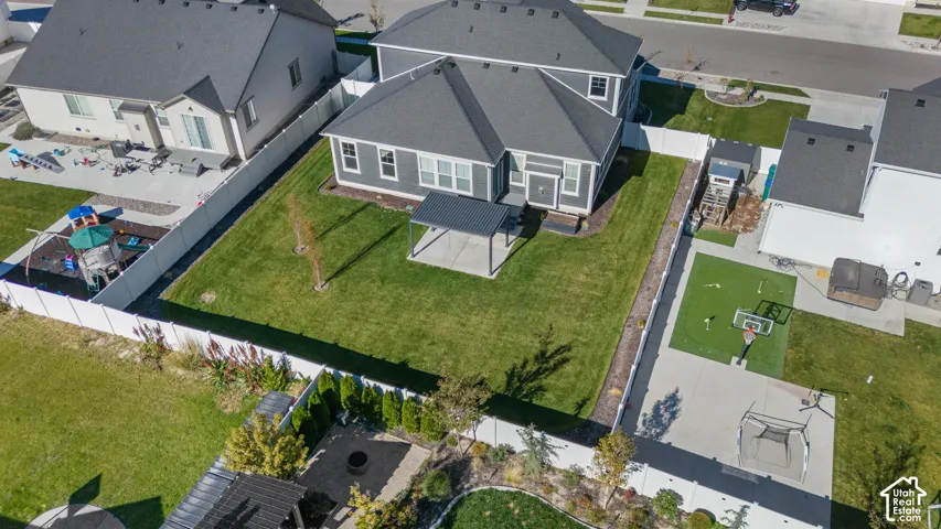 Fenced backyard featuring a manicured lawn, concrete patio with a metal pergola, and perimeter white vinyl fencing