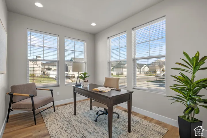 Room featuring wood-finish flooring, recessed lighting, and four large windows with horizontal blinds