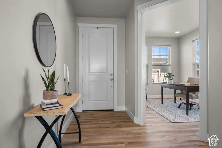 Entryway featuring neutral-toned walls, wood-finish flooring, a white paneled door with hardware, and clean architectural trim