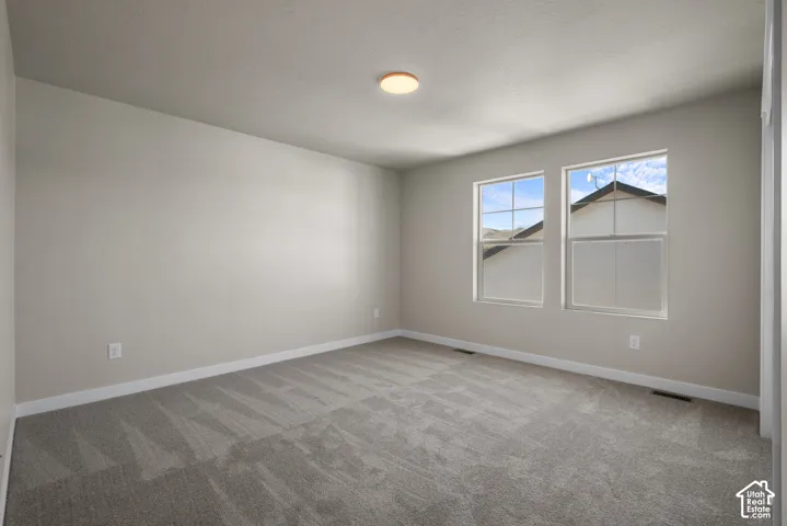 Room featuring neutral wall tones, plush wall-to-wall carpeting, two dual-pane grid windows, and a flush-mount ceiling light fixture