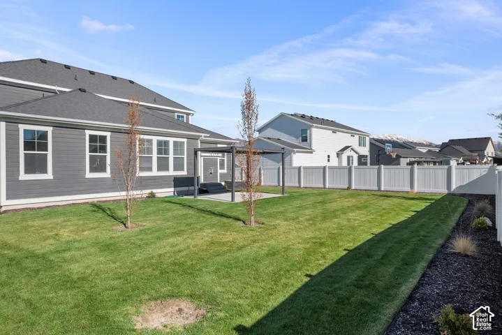 Private backyard featuring a concrete patio with a metal pergola, perimeter vinyl fencing, and wood-finish siding