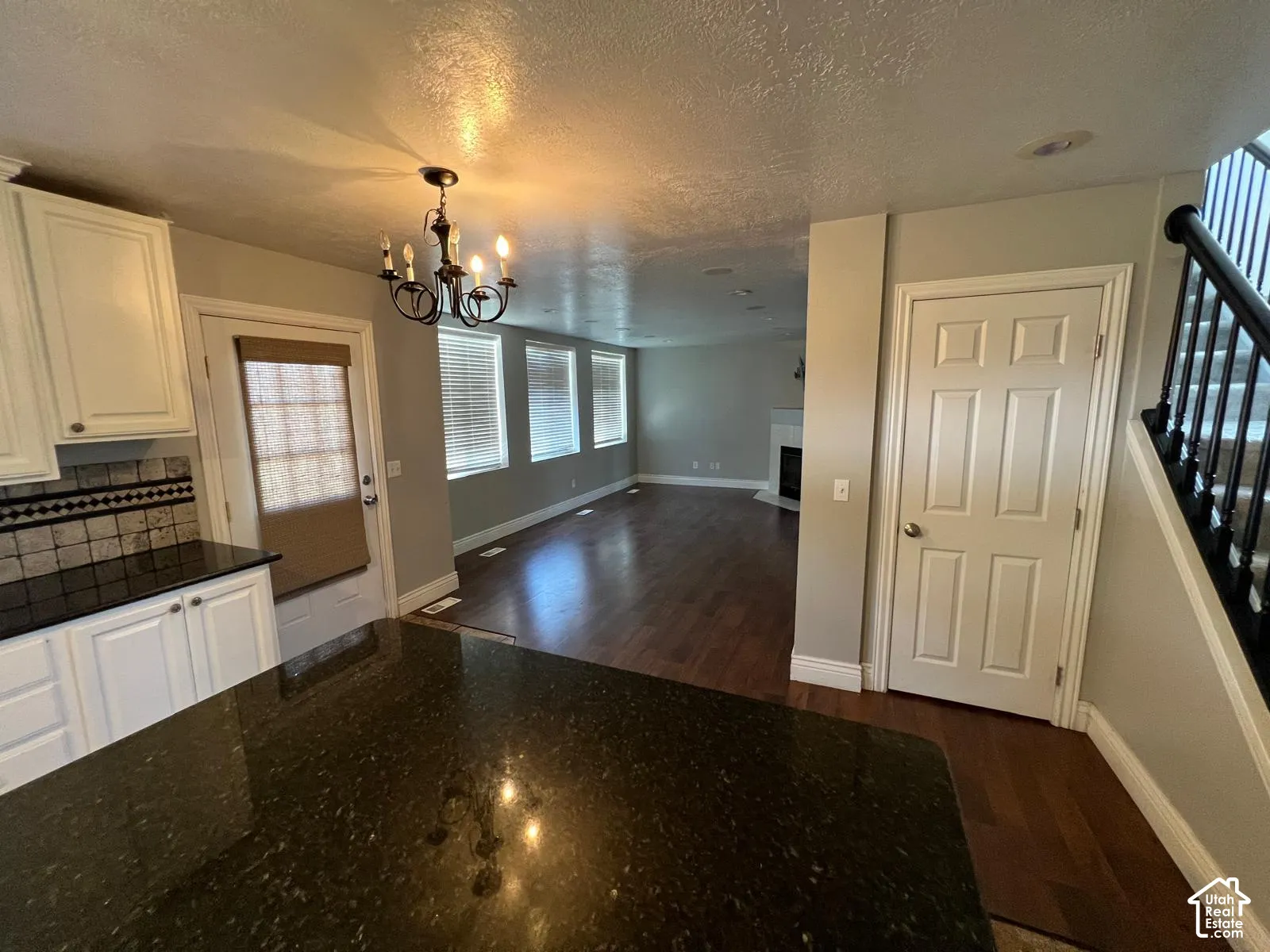 Kitchen featuring dark stone countertops, shaker-style cabinetry, a multi-arm chandelier, and wood-finish flooring