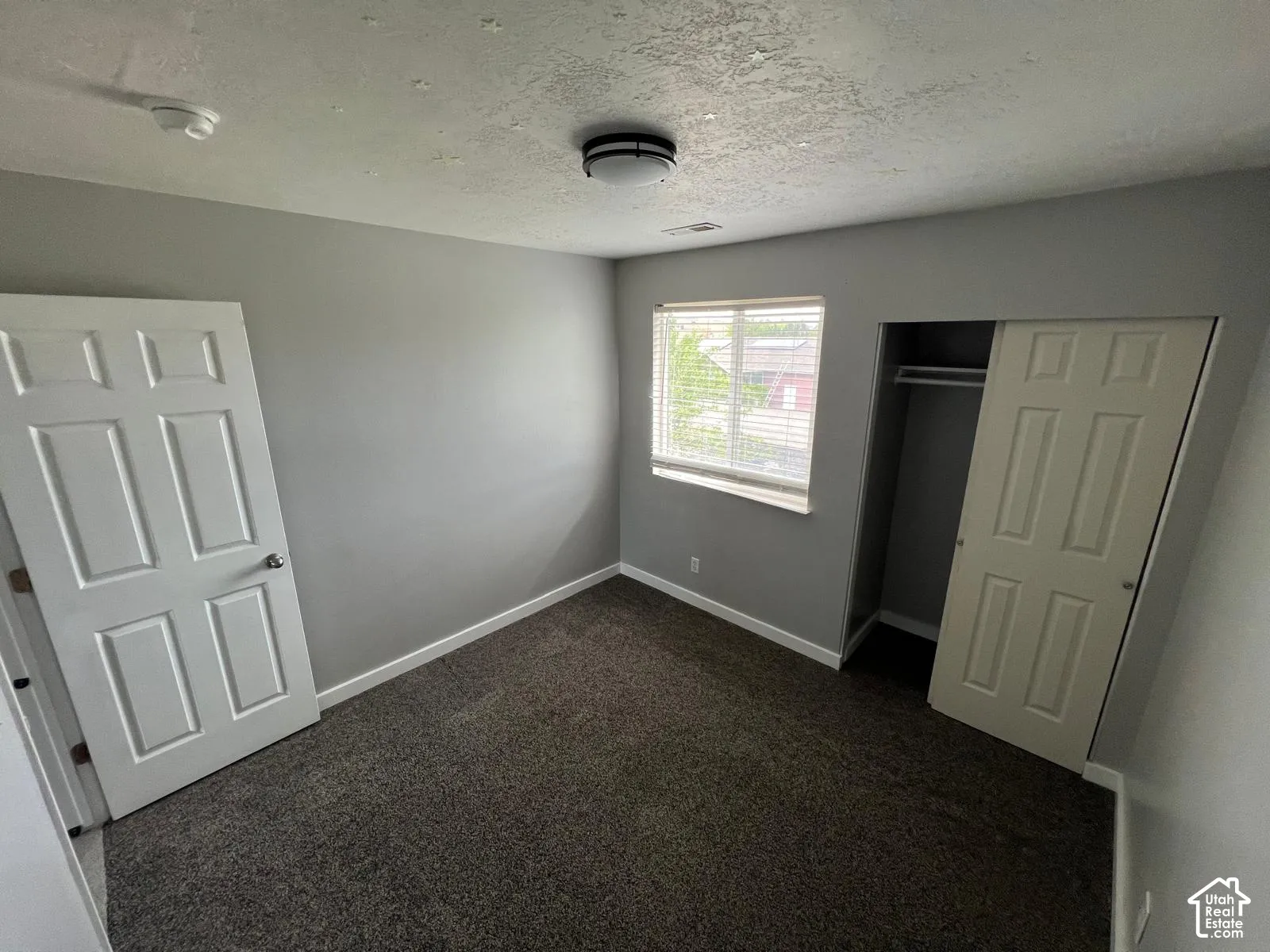 Room featuring neutral wall tones, wall-to-wall carpeting, a built-in closet with sliding doors, and a window with horizontal blinds