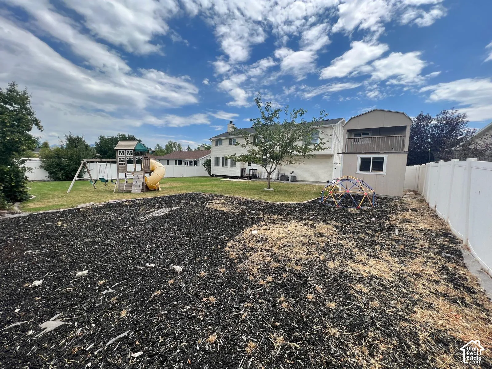 Backyard featuring a privacy fence, an elevated storage structure with a balcony, and mulch ground covering