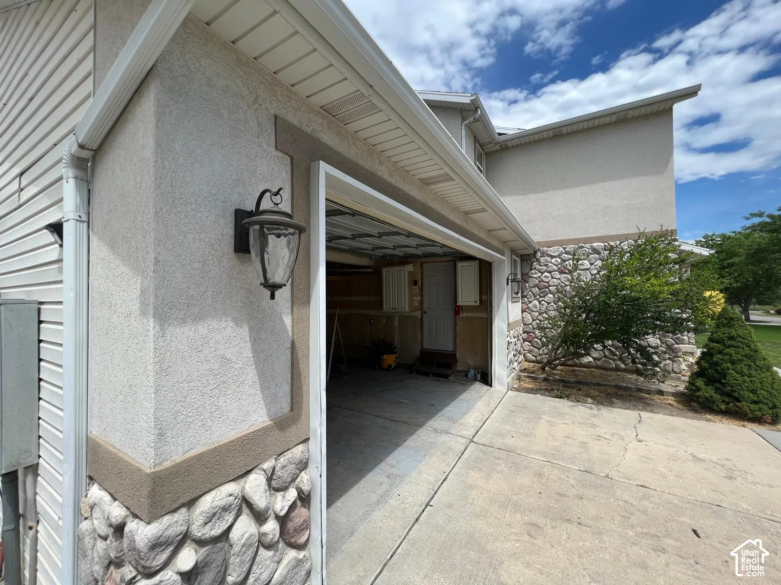 Exterior facade featuring stone veneer siding, horizontal lap siding, attached garage, and wall-mounted carriage-style lighting