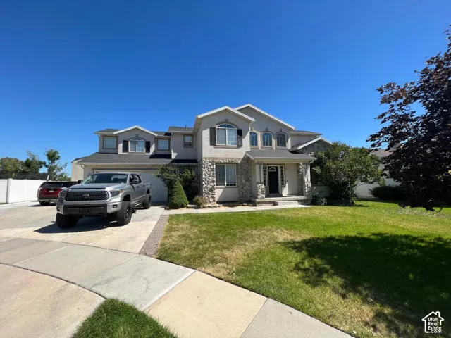 Multi-level residence featuring a stucco and stone exterior, arched window detailing, multi-gabled roofline, and an expansive concrete driveway