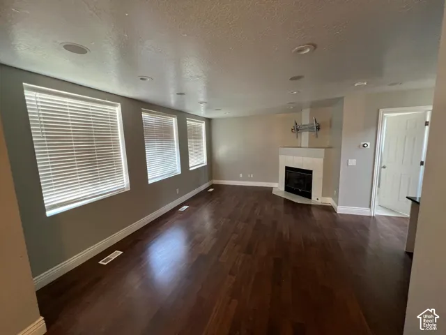 Open interior space featuring wood-finish flooring, recessed lighting, large windows with horizontal blinds, and a tile-surround fireplace