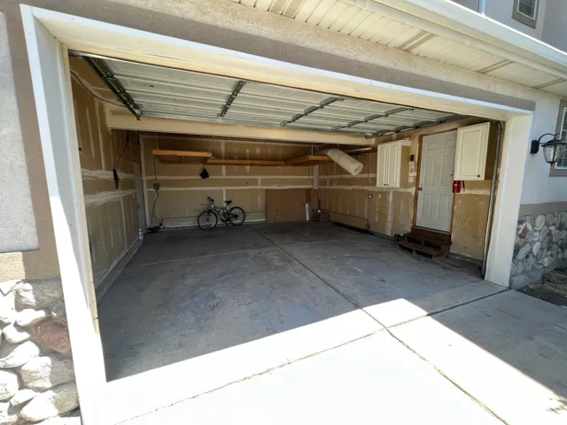 Two-car garage featuring a concrete floor, built-in wall-mounted cabinetry, overhead storage shelving, and a dedicated side entry door