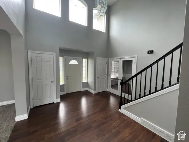 Foyer featuring a vaulted ceiling, wood-finish flooring, multi-pane transom windows, staircase with black balusters, and a glass-paneled entry door