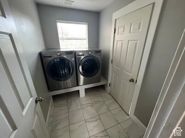 Laundry room featuring large-format tile flooring with a veined pattern, built-in elevated appliance platform, and a paneled interior door