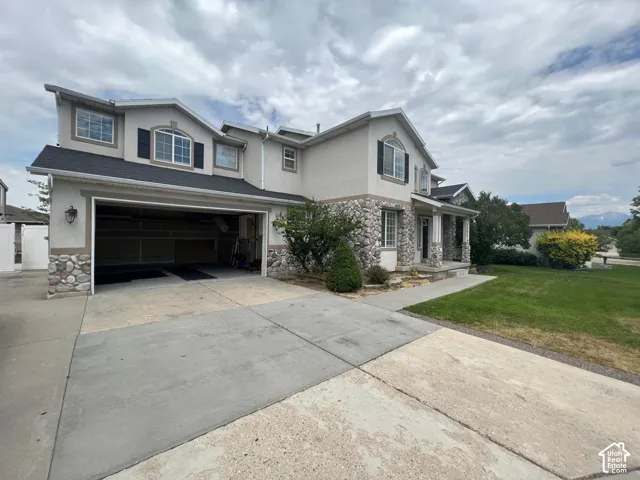 Multi-level exterior featuring stone veneer accents, stucco siding, arched window detailing, and a three-car garage