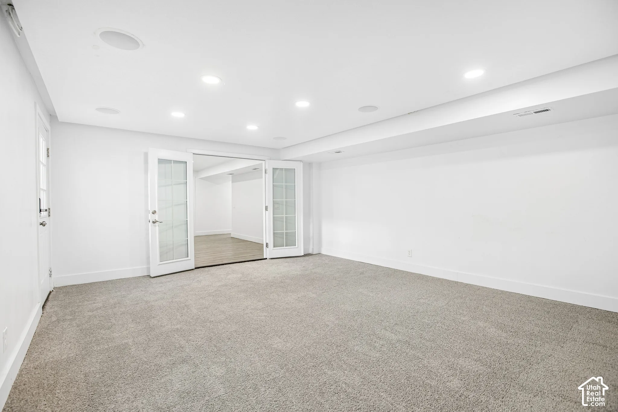 Interior space featuring wall-to-wall carpeting, recessed ceiling lighting, and double French doors with glass panes