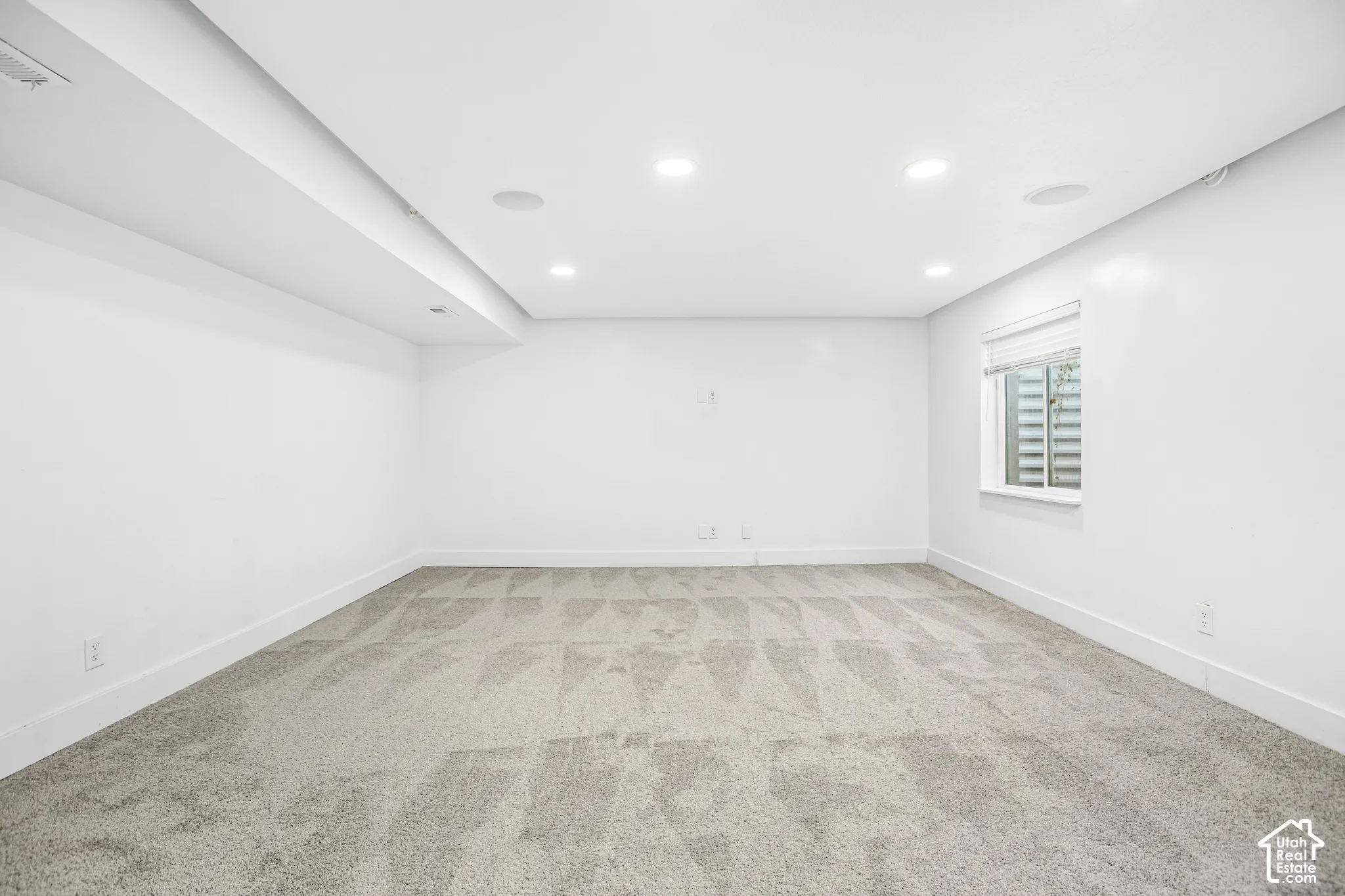 Room featuring recessed lighting, integrated ceiling speakers, wall-to-wall carpeting, and a rectangular egress window