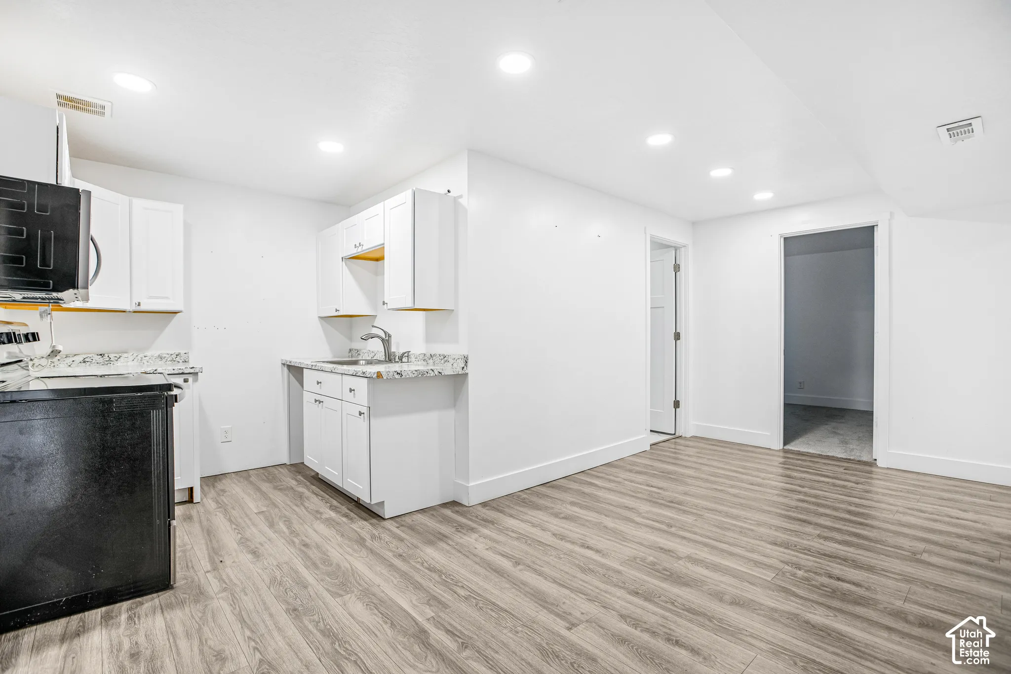 Kitchen featuring white cabinetry, stone-finish countertops, recessed lighting, and wood-finish flooring