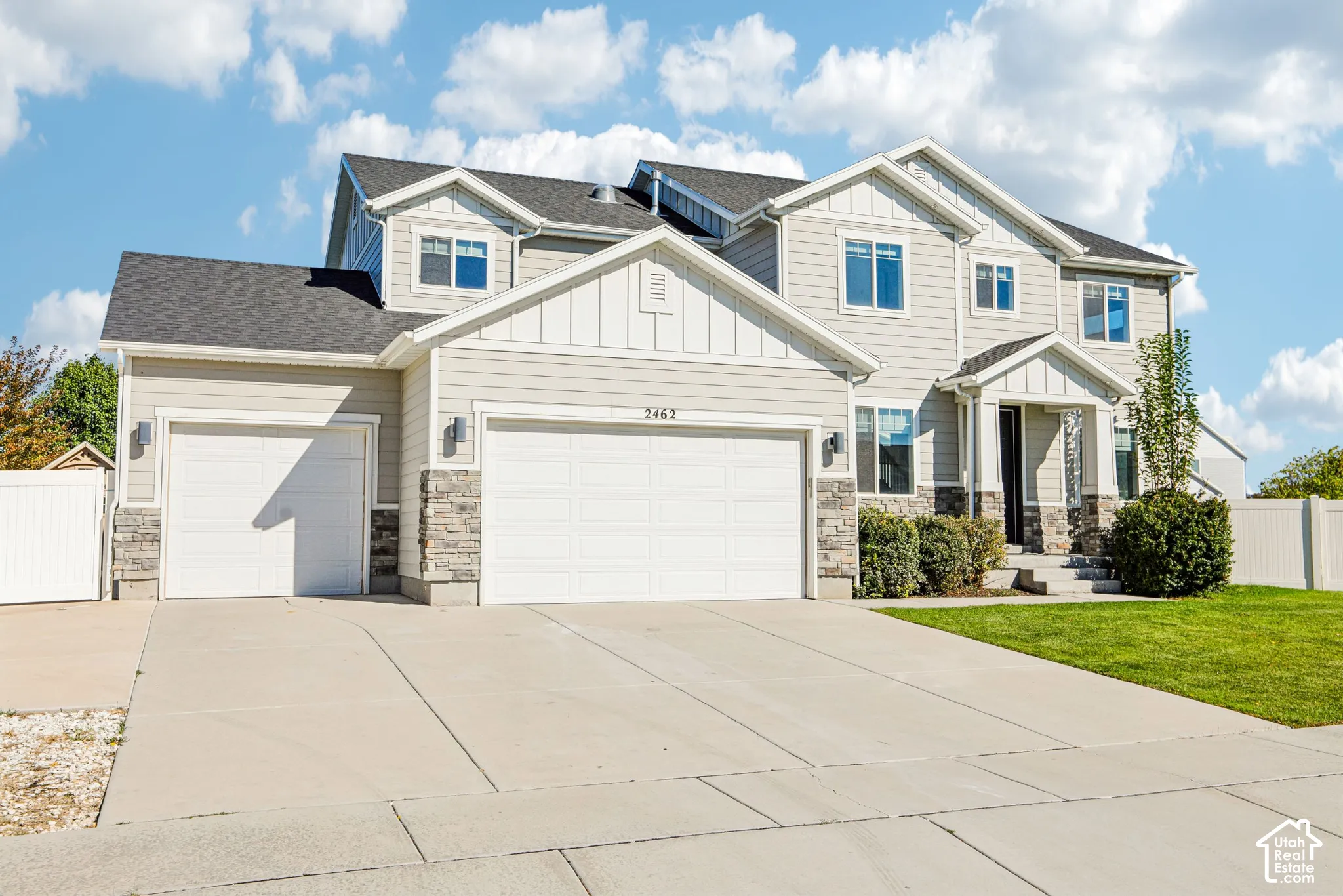 Multi-level exterior featuring horizontal siding, stone veneer accents, an asphalt shingle roof, three-car garage, and concrete driveway