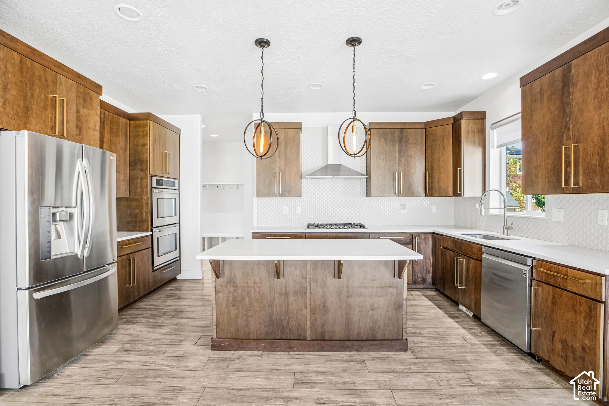 Kitchen featuring custom wood cabinetry, quartz countertops, a central island, stainless steel appliances, and wood-finish flooring