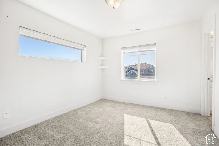 Neutral-toned wall-to-wall carpeting, horizontal and slider window configurations, and built-in corner shelving