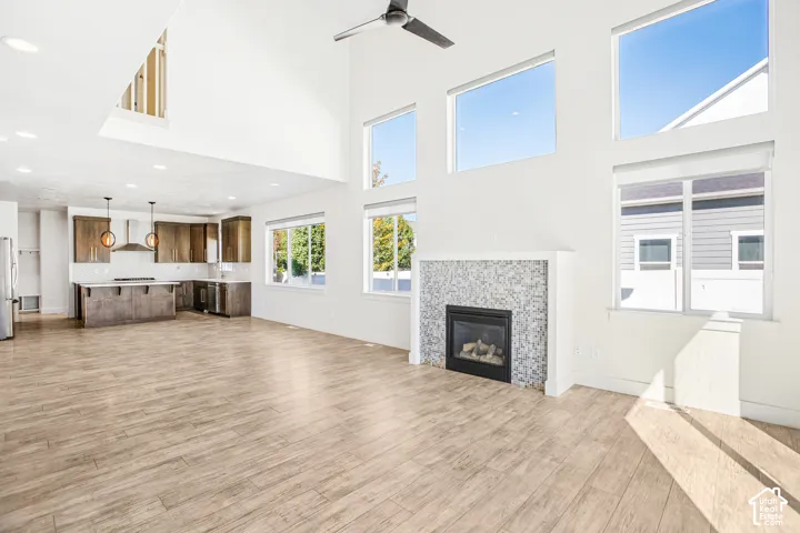 Open floor plan featuring vaulted ceilings, floor-to-ceiling windows, wood-finish flooring, a mosaic-tiled fireplace, and a kitchen with custom cabinetry and a center island