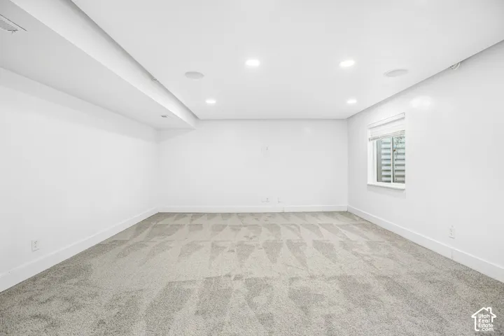 Room featuring recessed lighting, integrated ceiling speakers, wall-to-wall carpeting, and a rectangular egress window