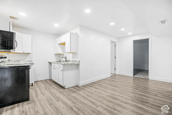 Kitchen featuring white cabinetry, stone-finish countertops, recessed lighting, and wood-finish flooring