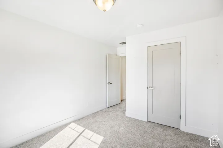 Room featuring neutral wall-to-wall carpeting, clean white wall finishes, and solid-core shaker-style interior doors with brushed nickel hardware, complemented by a flush-mount overhead light fixture