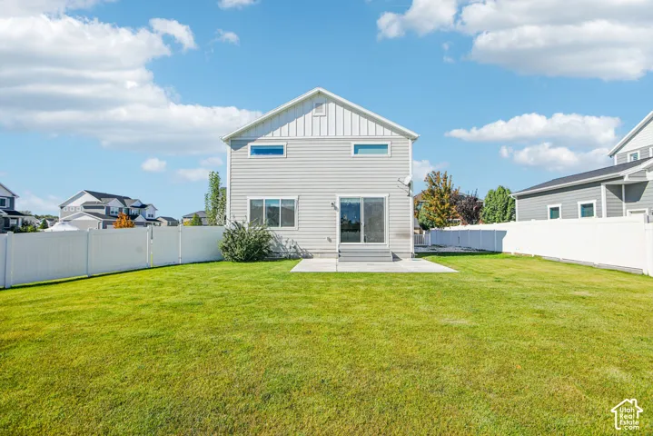 Rear exterior featuring horizontal lap siding, vertical board-and-batten gable detailing, a concrete patio, and a fully enclosed vinyl privacy fence