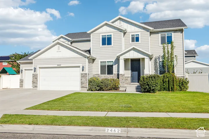 Two-story exterior featuring horizontal siding, stone veneer accents, multi-gabled roofline, three-car garage, and a covered front entryway