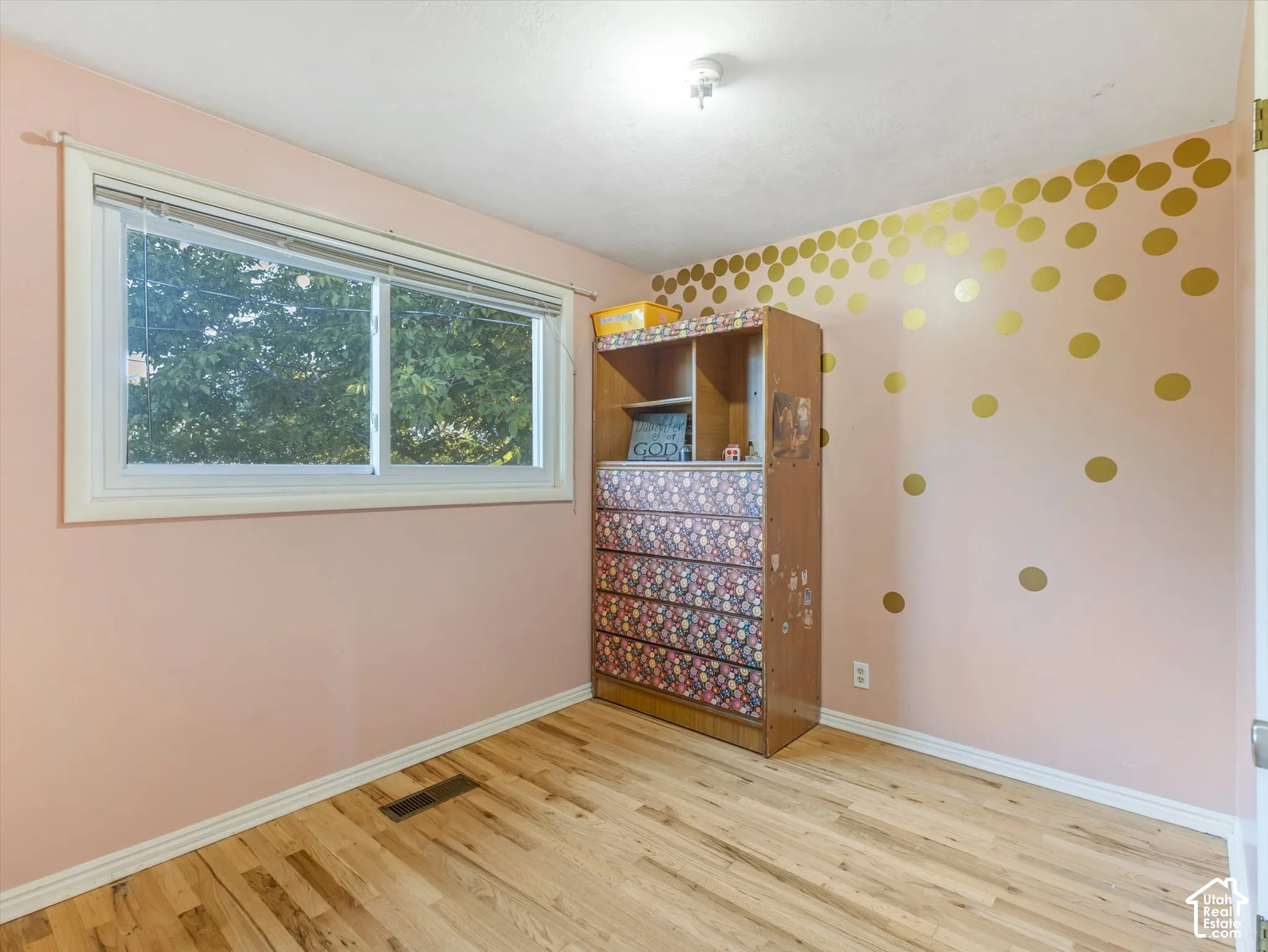 Room featuring wood-finish flooring, a single-pane sliding window with white trim, and a ceiling-mounted light fixture