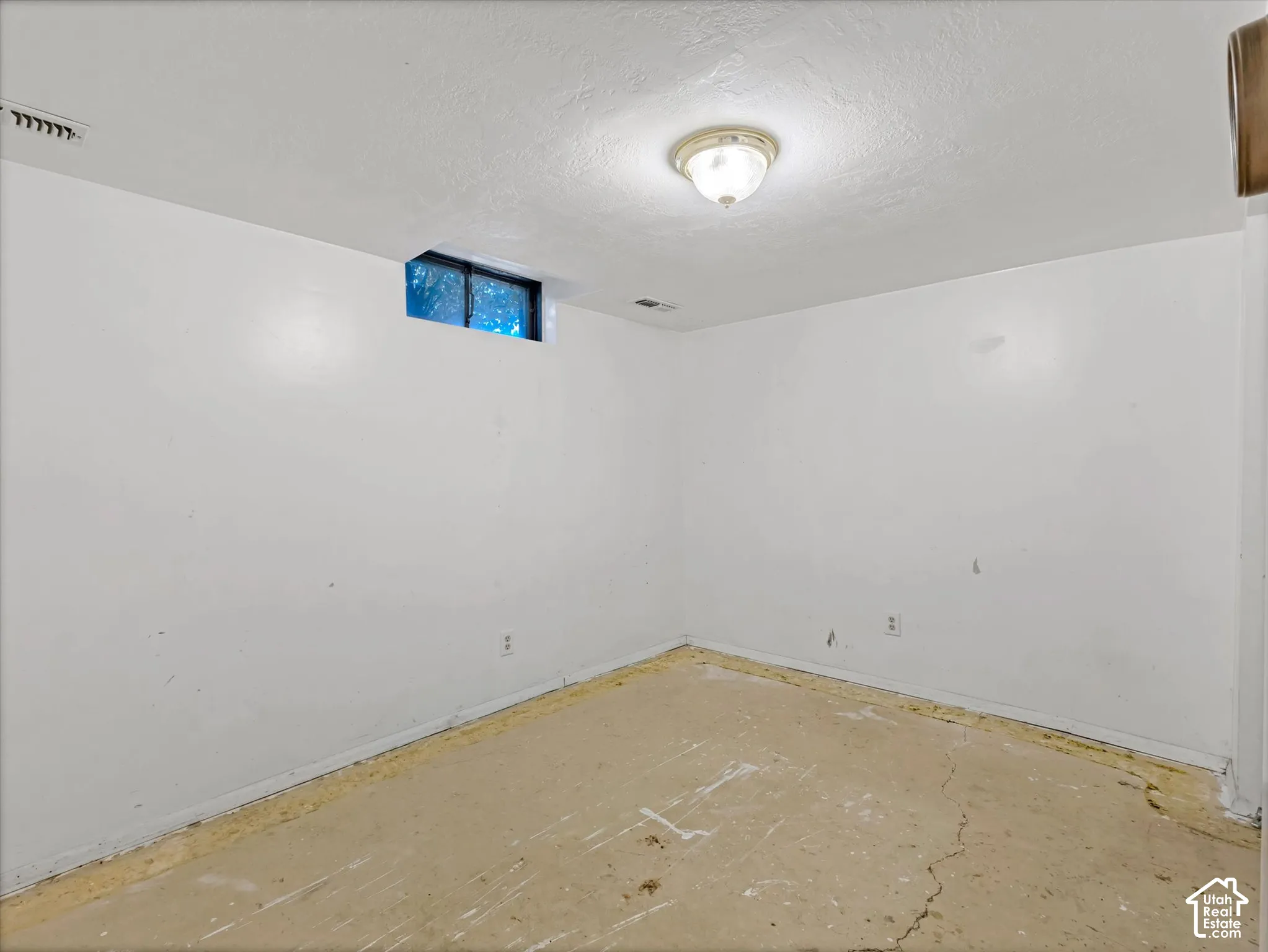 Interior space featuring smooth-finish white walls, a single-bulb flush-mount ceiling light, and a high-set slider window