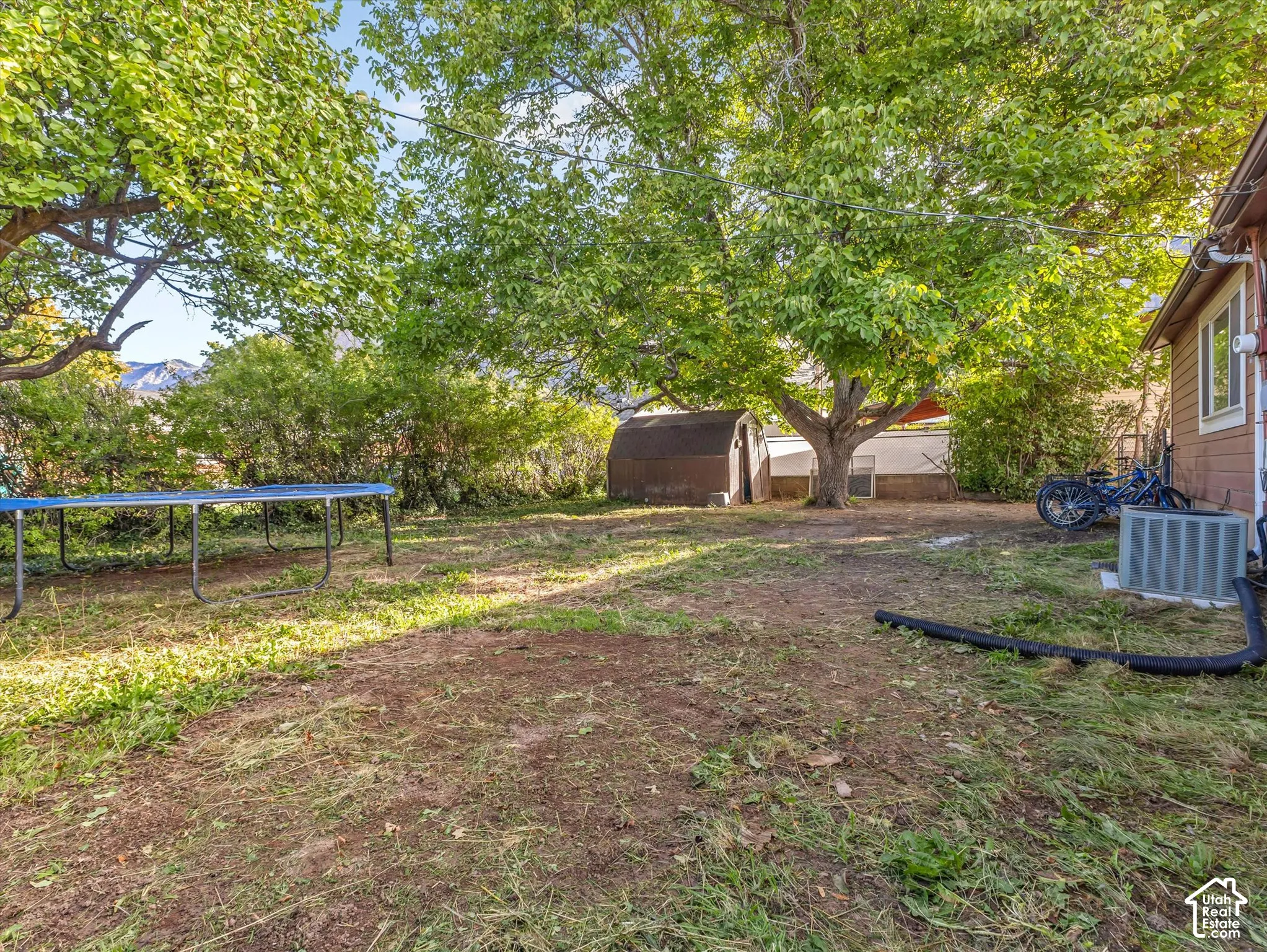 Backyard featuring mature trees, a detached shed, and exterior mountain scenery