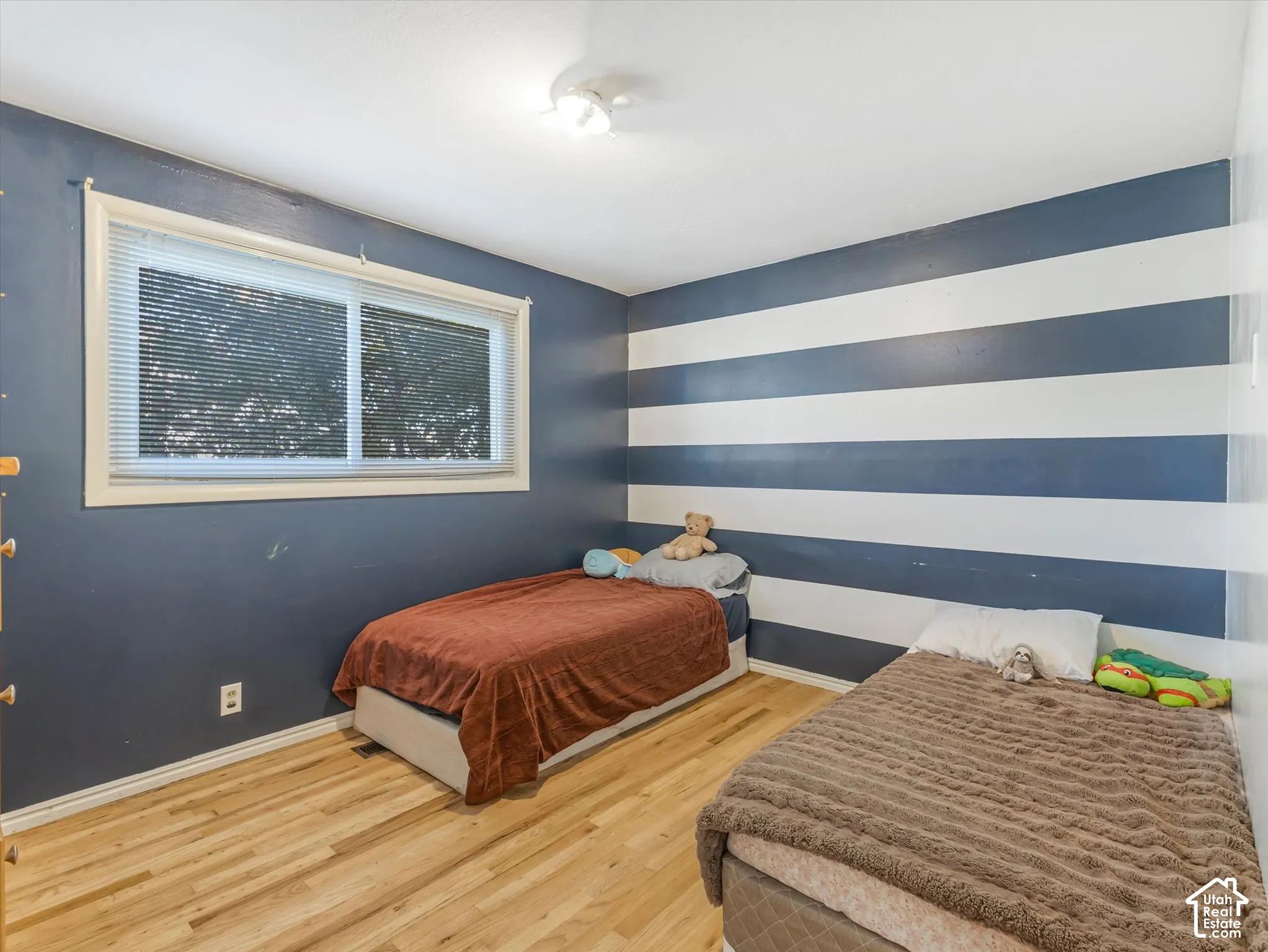 Interior space featuring wood-finish flooring, a sliding window with horizontal blinds, and a ceiling-mounted light fixture