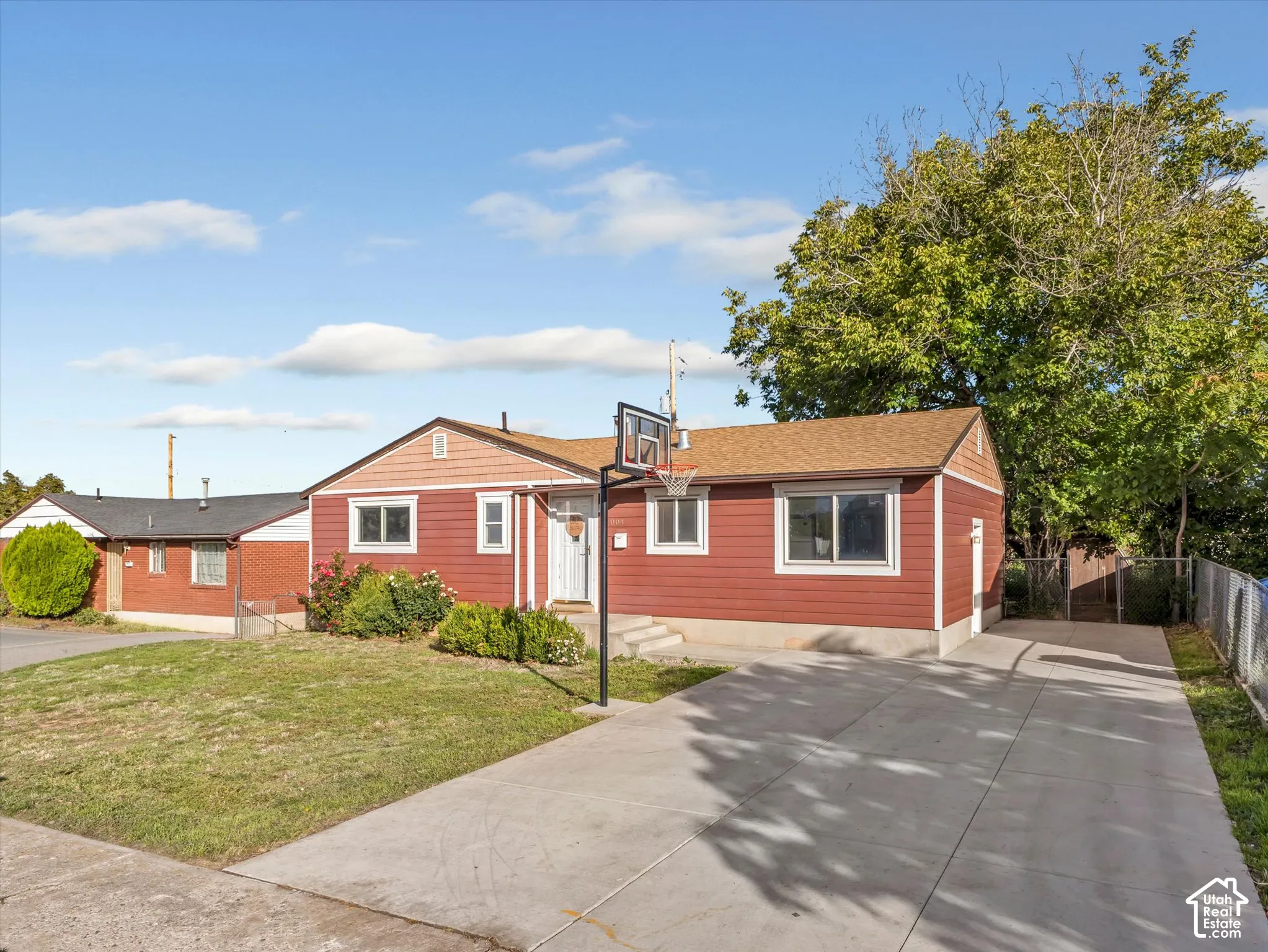 Single-story exterior featuring horizontal lap siding, a shingled roof, a concrete driveway, and established landscaping