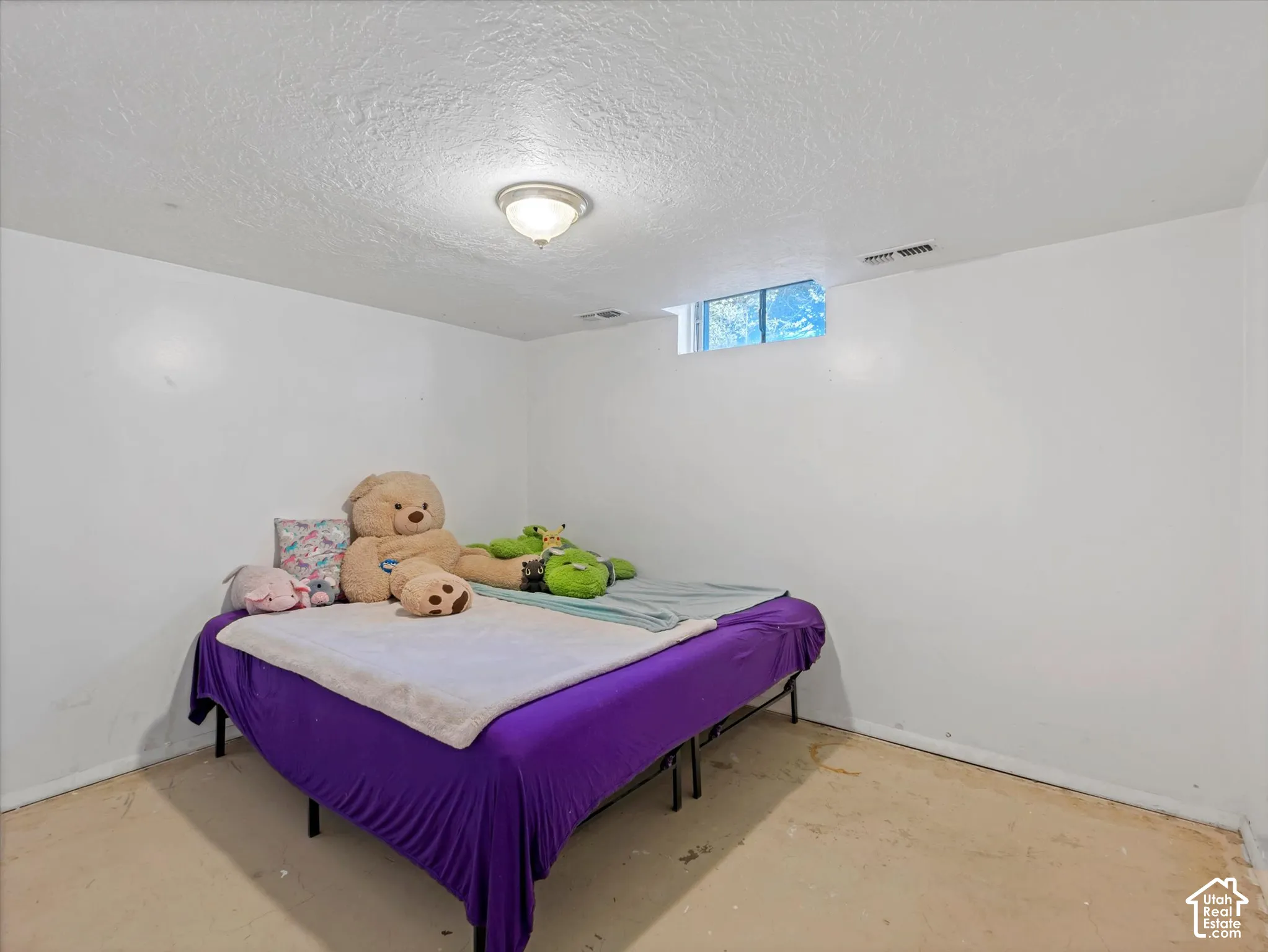 Interior room featuring smooth white walls, a flush-mount ceiling light fixture, and a rectangular egress window