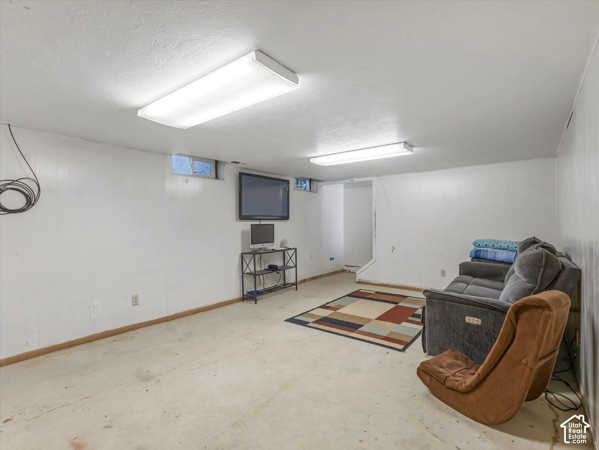 Finished lower level space featuring painted paneling, dual flush-mount ceiling light fixtures, and high-set slider windows
