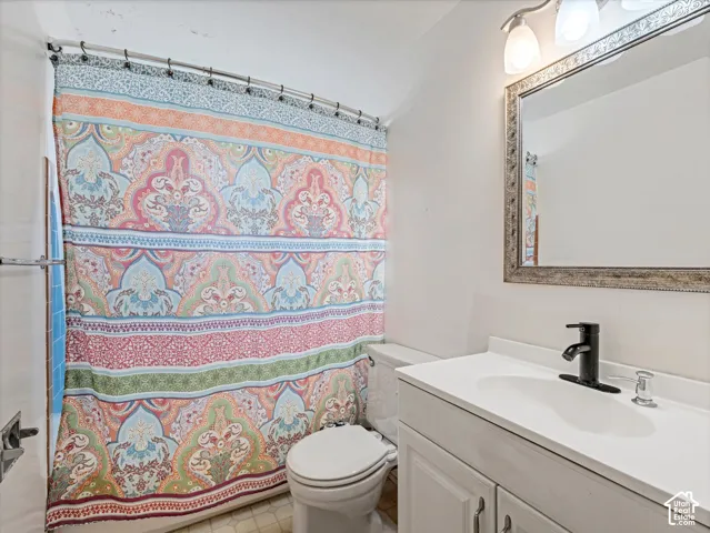 Bathroom featuring a white vanity cabinet with an integrated white sink, matte black faucet, wall-mounted light fixture, and framed mirror