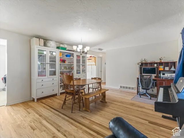 Open-concept space featuring light-toned wood-finish flooring and a multi-arm chandelier