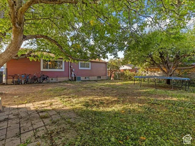 Exterior features include red horizontal siding, a stone paver patio, and mature trees providing shade across the grounds